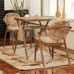 a dining room table with chairs and a rug on the floor in front of it