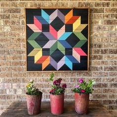 three potted plants sitting on top of a wooden table next to a brick wall