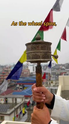 a person holding a pole with flags in the background and an inscription above it that reads as the wheel spins,