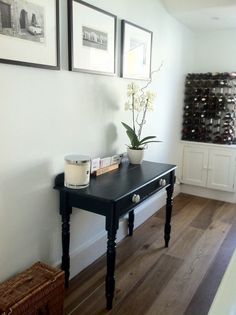 a black table with two vases on it next to a wall filled with wine bottles