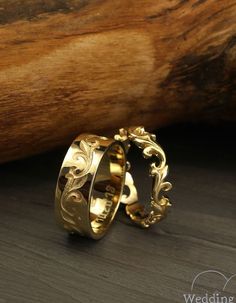 two gold wedding rings sitting on top of a wooden table