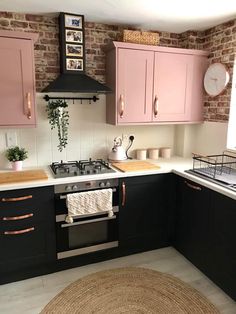 a kitchen with black cabinets and pink cupboards on the walls, an area rug in front of the stove