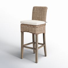 a wicker bar stool with a cushion on the seat and backrest, in front of a white background