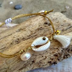 This elegant Sea Shell Bracelet, boho and hippie style, is handmade with love from Greece. This   fashionable summer bracelet consists of a natural white cowrie shell, adorned with a sparkling rhinestone, a cute white tassel, a fresh water pearl and gold plated brass beads, all knotted with a golden waxed thread. It's adjustable, with a slide macrame knot, in order to fit any wrist size and wearable either on its own, or layered with your other bracelets. You can wear it as an anklet, too! The u Bohemian Gold Bracelets With Sliding Knot, Bohemian Gold Resizable Friendship Bracelets, Gold Bohemian Resizable Friendship Bracelets, Gold Bohemian Beaded Bracelets For Vacation, Bohemian Gold Beaded Bracelets For Vacation, Bohemian Hand Wrapped Bracelets For Vacation, Bohemian Hand-wrapped Bracelets For Vacation, Bohemian Jewelry With Sliding Knot For Vacation, Bohemian Resizable Bracelets For Vacation