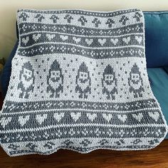 a crocheted blanket sitting on top of a couch next to a blue pillow