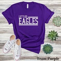 Get ready to soar with our "Let's Go Eagles" T-shirt! Perfect for students, teachers, alumni, and fans, this tee is the ultimate way to rally behind your team and show your Eagle pride. This classic unisex jersey short sleeve tee fits like a well-loved favorite. Soft cotton and quality print make users fall in love with it over and over again.  .: 100% Airlume combed, and ring spun cotton (fiber content may vary for different colors) .: Light fabric (4.2 oz/yd² (142 g/m .: Retail fit .: Tear away label .: Runs true to size CARE INSTRUCTIONS Wash item inside out in cold water Do not bleach Do not dry clean Do not iron directly on the design. Tumble dry low. NOTE: All apparel items from Chosen Chic are Direct to Garment printing which means the design is print into the fibers of that fabric Team-colored T-shirt For School Spirit Fan Gear, Team-colored T-shirt With Text Print For Fans, Sports Fan T-shirt With Screen Print For College, Casual Fan Gear T-shirt With Team Name, College T-shirt With Team Spirit Letter Print, Sports Fan T-shirt With Team Name For College, Team Spirit T-shirt With Text Print For Fans, College Team Spirit T-shirt With Team Name, College T-shirt With Team Name And Team Spirit