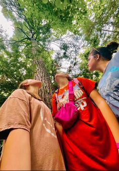 three people standing in front of a tree looking up at the sky