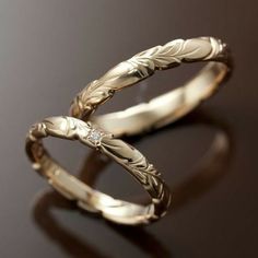 two gold wedding rings with leaves and diamonds on them, sitting on a brown surface