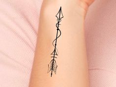 a woman's arm with an arrow tattoo on it