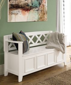 a white bench sitting in front of a window next to a painting on the wall