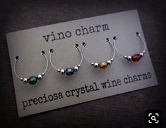 three wine charms sitting on top of a piece of paper next to a sign that says vino charm