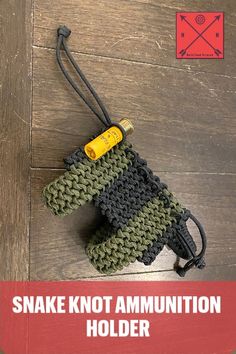 a small green and black bag on top of a wooden floor with the words snake knott annition holder