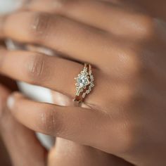 a woman's hand with a diamond ring on her left hand and the other hand holding an engagement ring