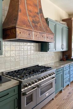 a stove top oven sitting inside of a kitchen next to blue cabinets and counter tops