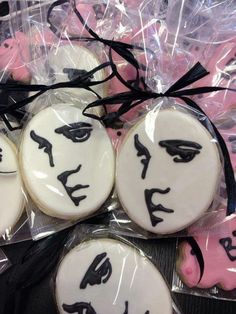 decorated cookies with faces on them in plastic wrappers and black ribbon tied around the edges