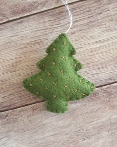 a green felt christmas tree ornament hanging from a string on a wooden table