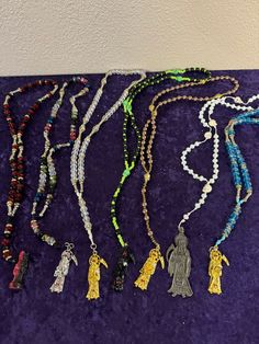 several beaded necklaces are displayed on a purple surface