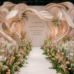 A stunning, rustic setup for a special event or celebration. The scene features a beautifully decorated wooden panel with vertical slats, providing a charming backdrop. Lush green foliage adds a touch of nature, complementing the large floral arrangement of dried and fresh flowers on the left. Above the wooden table, three decorative hanging lanterns made of woven material cast a warm, inviting glow. The table is laden with delectable cakes and other decorative items, while a smaller round table in front, draped with a brown cloth, holds a pristine white cake. The overall atmosphere is both rustic and elegant, with a natural theme accentuated by the wood, greenery, and floral elements. Wedding Decor Nature Theme, White Drapes Wedding, Unique Wedding Backdrop, Backdrop Cake Table, Weddings Decorations Elegant Romantic, Reception Table Design, Vertical Slats, Wedding Wishlist, Wedding Hall Decorations