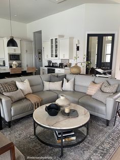 a living room filled with furniture next to a kitchen and dining room table on top of a rug