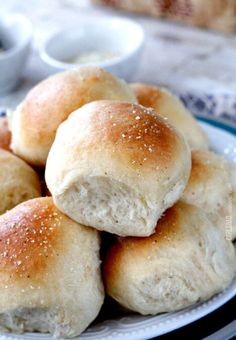 rolls piled on top of each other on a plate with dipping sauces in the background