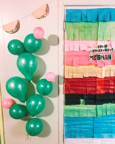 balloons and streamers are hanging on the wall in front of a door decorated with ribbons