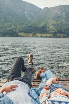 there are two people laying on the dock with their feet in the water and one is holding a teddy bear