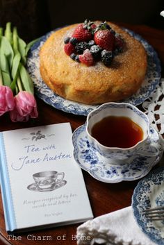 a table topped with plates and cups filled with tea next to a cake on top of a wooden table