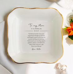 a white and gold plate with a poem written on it next to some orange flowers