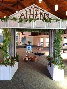 the entrance to an airport with plants growing out of it's pillars and welcome signs