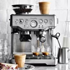 an espresso machine sitting on top of a counter next to plates of pastries