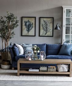 a living room with blue couches and pictures on the wall above it's coffee table