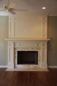 an empty living room with a fireplace and ceiling fan