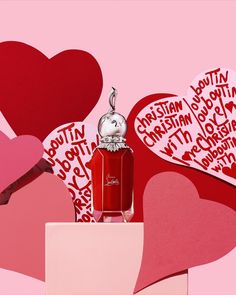 a bottle of perfume surrounded by hearts on a pink background