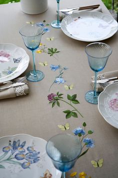 the table is set with plates, glasses and flowers painted on it's side