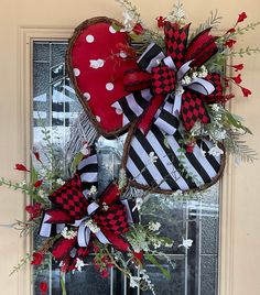 two heart shaped wreaths with red and black bows hanging from the front of a door