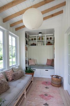 a living room with white walls and wooden beams on the ceiling is filled with bookshelves