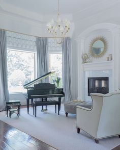 a living room filled with furniture and a piano in front of a fire place under a chandelier