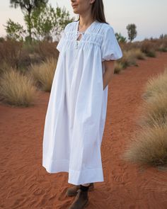 a woman standing in the desert wearing a white dress