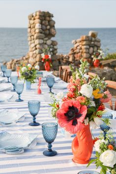 an outdoor table set with blue and white plates, vases and flowers on it