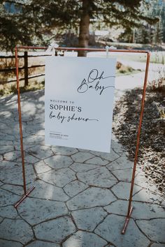 a sign that is on the side of a road next to a fence and trees