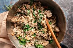 a bowl filled with meat and spinach on top of a wooden spoon next to a napkin