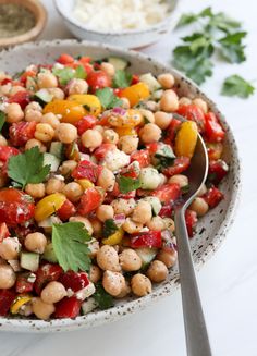 a salad with chickpeas, tomatoes, cucumbers and parsley in a bowl