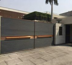 a large metal gate in front of a building with palm trees on the other side