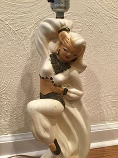 a statue of a woman dancing on top of a lamp