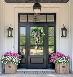 two planters with pink and white flowers sit in front of a black double door