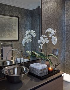 a bathroom sink and mirror with white flowers in the center, candles on the counter