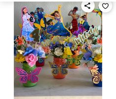 a table topped with vases filled with flowers and fairy figurines