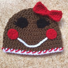 a brown crocheted hat with a red bow on it's head and eyes