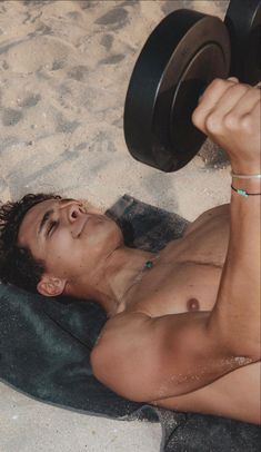 a shirtless man laying on the ground with a barbell