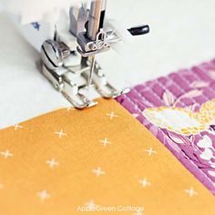 the sewing machine is working on an orange and pink quilting material that has been sewn